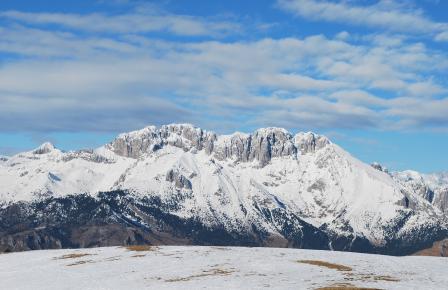 Montagne innevate sotto un cielo azzurro con nuvole sparse.